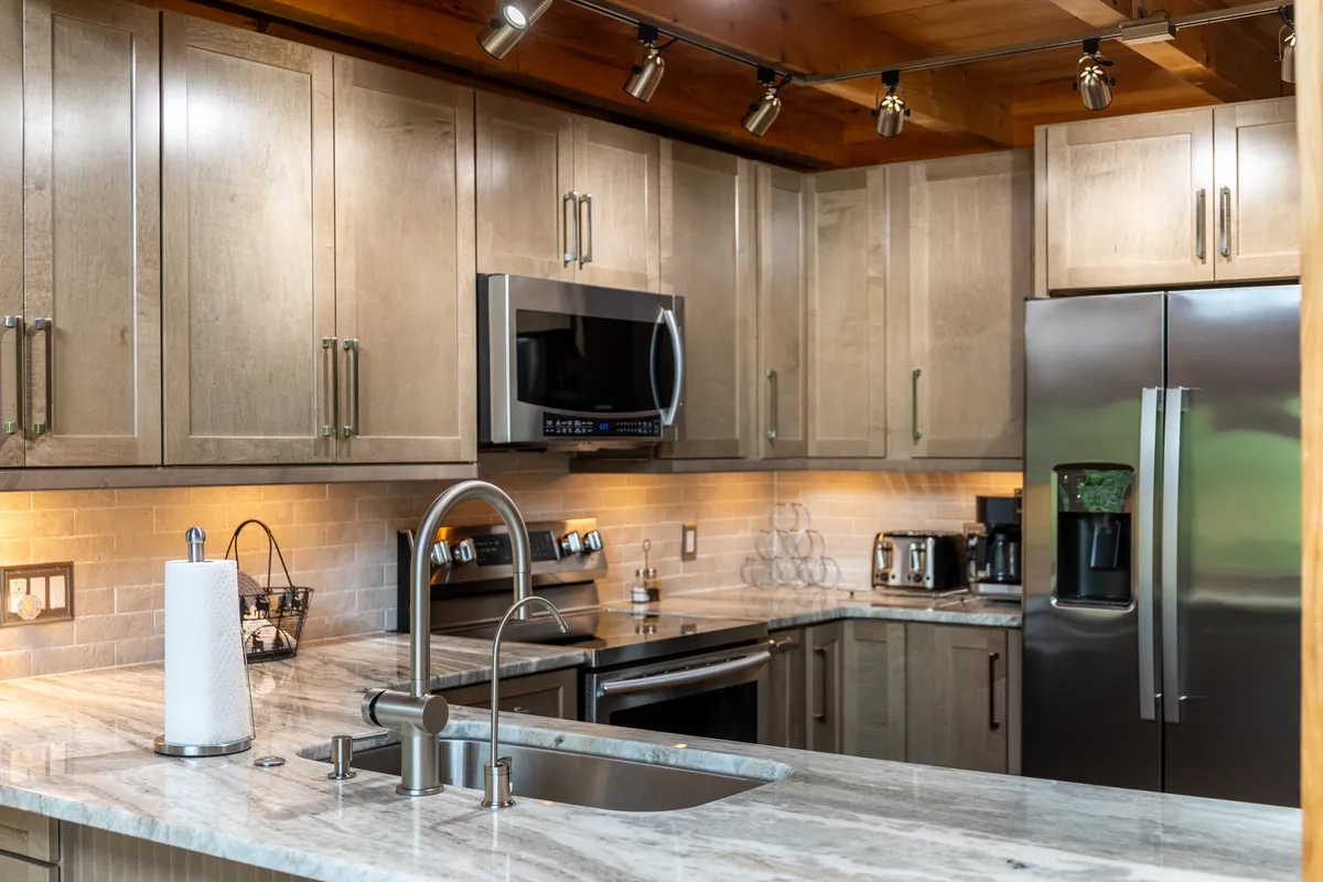 A close-up view of the kitchen area, featuring granite countertops, stainless steel appliances, and warm wooden cabinetry, highlighting the gourmet conveniences available for home-cooked meals.